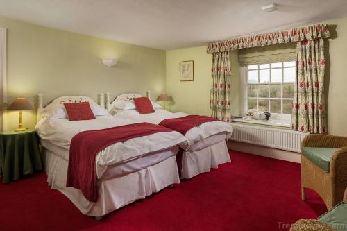 a bedroom with two beds and a window at Trenderway Farm in Looe