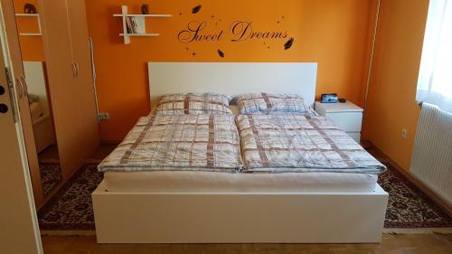 a bed in a bedroom with an orange wall at Garden Apartment Donau-City (P&R) in Vienna