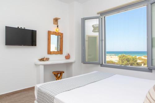 a bedroom with a bed and a large window at Salinus Beachfront Private Pool Villas in Plaka