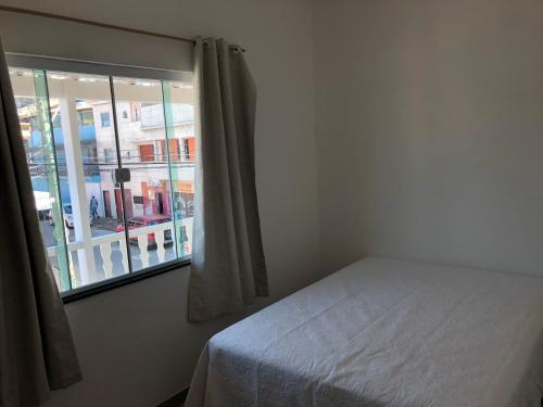 1 dormitorio con cama y ventana en Kitnet Central II, en Arraial do Cabo