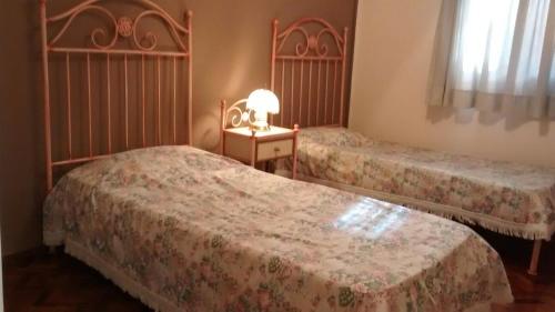 ein Schlafzimmer mit zwei Betten und einem Tisch mit Lampe in der Unterkunft Departamentos Mendoza in Mendoza