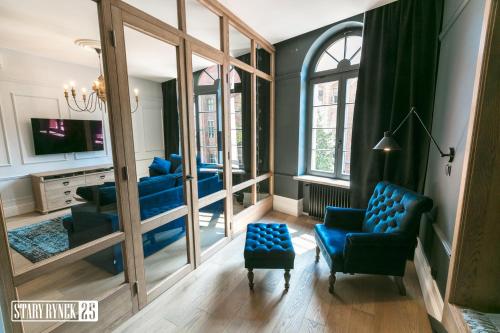salon z niebieskimi krzesłami i lustrem w obiekcie Apartamenty Stary Rynek 25 Toruń w Toruniu