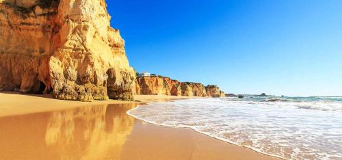 a beach with a large cliff and the ocean at Rotunda da Marina in Portimão