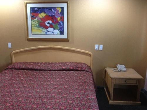 a bedroom with a bed and a picture on the wall at All 8 Motel in Azusa