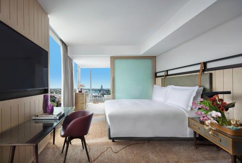 a bedroom with a bed and a desk and a television at Sofitel Sydney Darling Harbour in Sydney