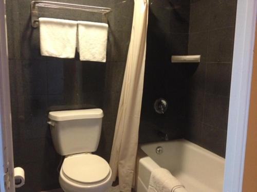 La salle de bains est pourvue de toilettes blanches et d'une baignoire. dans l'établissement All 8 Motel, à Azusa