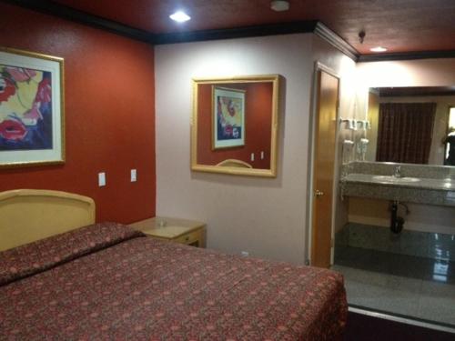 a bedroom with a bed and a bathroom with a sink at All 8 Motel in Azusa