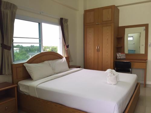 Schlafzimmer mit einem großen weißen Bett und einem Fenster in der Unterkunft Surin Mansion in Surin