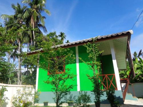 a green facade of a house with trees at Sarm Mork Guest House in Mae Hong Son