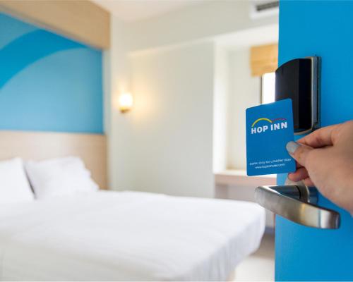 a person holding up a hotel room door with a hor inn card at Hop Inn Hotel Ermita Manila in Manila