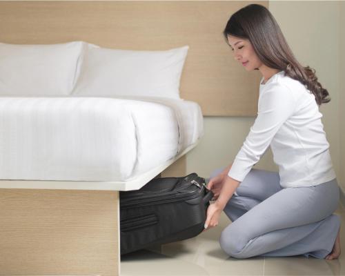 a woman kneeling next to a bed with a suitcase at Hop Inn Hotel Ermita Manila in Manila