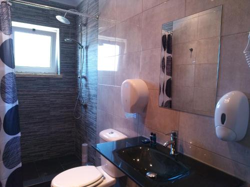 a bathroom with a sink and a toilet and a window at Fonte da Telha Beach Hostel in Costa da Caparica