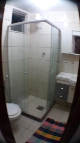 a bathroom with a toilet and a glass shower at Apartamento Orquídea in Campos dos Goytacazes