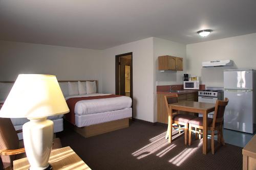 a hotel room with a bed and a table and a kitchen at Aladdin Inn and Suites in Portland