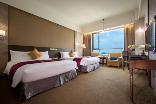 嘉義市にあるロイヤル チアーイー ホテルのベッド2台とデスクが備わるホテルルームです。