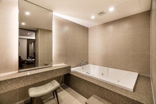 uma casa de banho com uma banheira, um lavatório e um banco em WD Hotel em Seul
