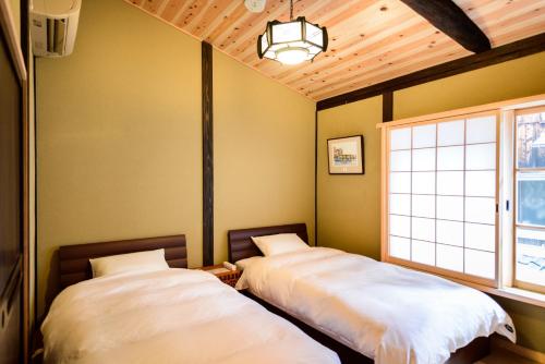 two beds in a room with a window at Nadeshiko Shirakawa Machiya House in Kyoto