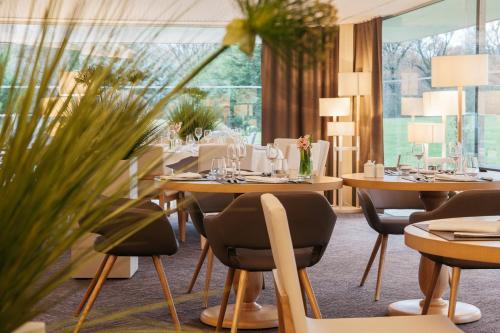 a restaurant with tables and chairs and plants at Best Western Le Bois de la Marche in Poitiers