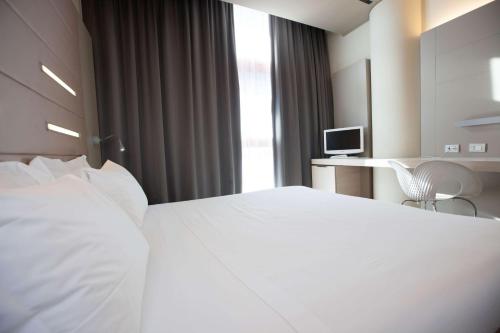a hotel room with a white bed and a desk at Best Western Plus Net Tower Hotel Padova in Padova