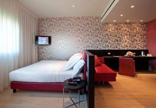 a bedroom with a bed and a desk with a television at Devero Hotel & Spa, BW Signature Collection in Cavenago di Brianza