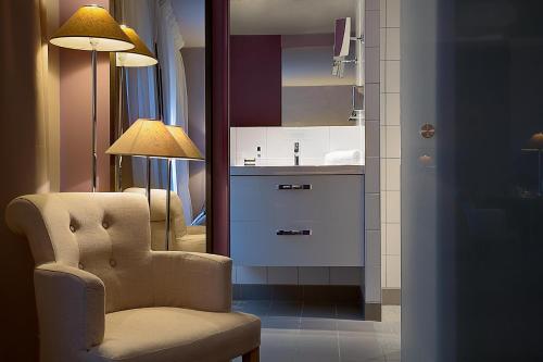 a living room with a chair and a sink at Best Western Hotel de la Breche in Niort