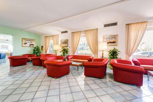 a waiting room with red chairs and tables and windows at Best Western Hotel La Solara in Sorrento