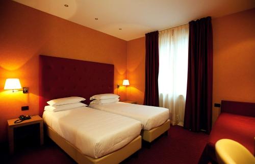 a hotel room with two beds and a window at Best Western Hotel Piemontese in Bergamo