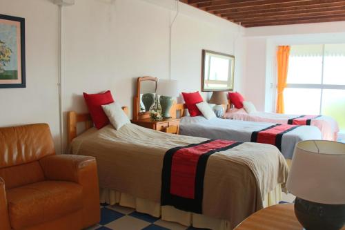 a bedroom with three beds and a chair and a window at Minamiboso Asian Garden Villa Shirahama in Minamiboso
