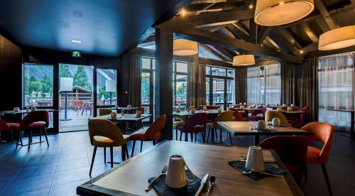 a restaurant with tables and chairs and windows at Excelsior Chamonix Hôtel & Spa in Chamonix-Mont-Blanc