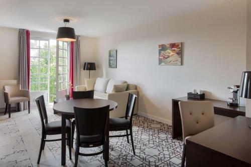 a room with a table and chairs and a living room at Best Western Blanche de Castille Dourdan in Dourdan