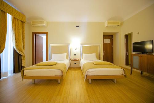 a bedroom with two beds and a flat screen tv at Best Western Crystal Palace Hotel in Turin