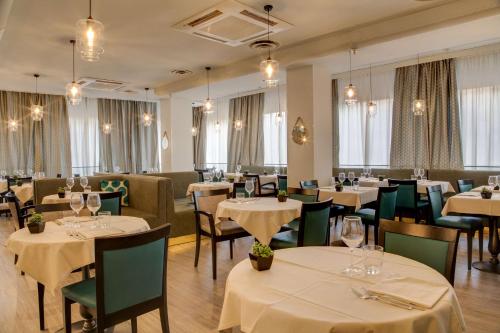 a restaurant with white tables and chairs and windows at Best Western Plus CHC Florence in Florence