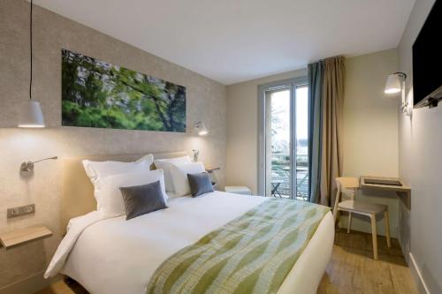 une chambre d'hôtel avec un grand lit et un bureau dans l'établissement BEST WESTERN La Porte des Châteaux, à Meung-sur-Loire