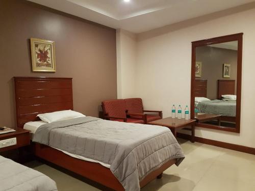 a bedroom with a bed and a mirror and a chair at Hotel Subhalakshmi Palace in Kāraikkudi