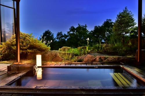 a pool of water with a candle in a garden at Tateshina Park Hotel in Chino