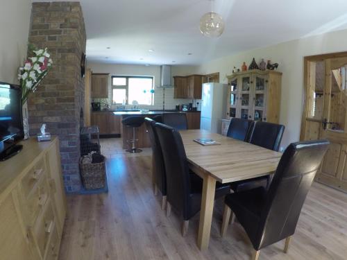 a kitchen and dining room with a wooden table and chairs at Barnagowlane House in Barnagowlane