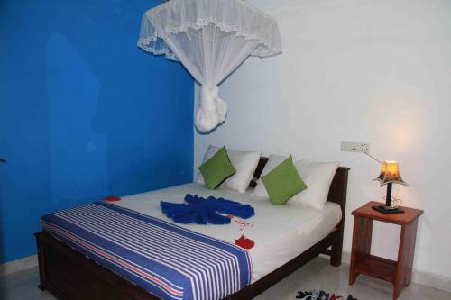 a bedroom with a bed with a blue wall at Senura Home Stay in Sigiriya