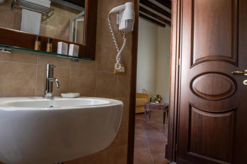 La salle de bains est pourvue d'un lavabo blanc à côté d'une porte. dans l'établissement Hotel Residenza Petra, à Petralia Soprana