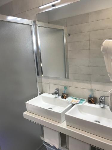a bathroom with two sinks and a mirror at Villaggio La Pescaccia in San Clemente