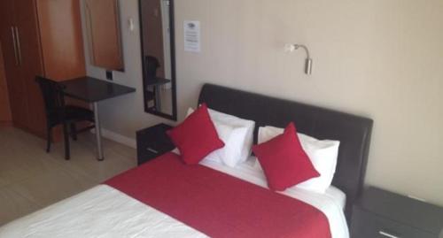 a bedroom with a bed with red and white pillows at B.R.O.Homes and Villas in Port Elizabeth