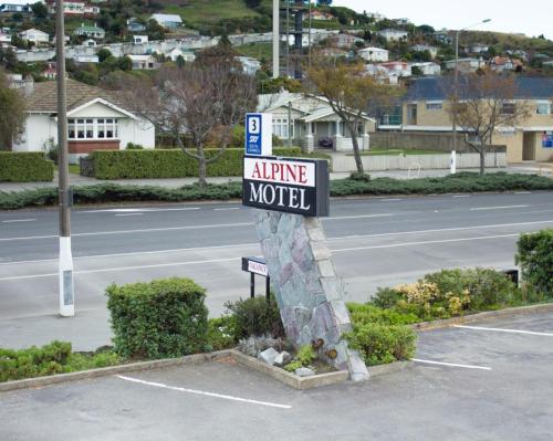 a parking lot with an airplane motel sign on a street at Alpine Motel in Oamaru