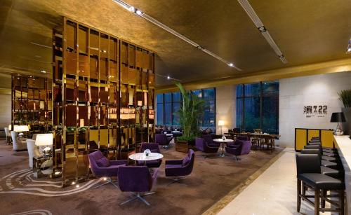 a restaurant with purple chairs and tables and windows at Radisson Blu Plaza Chongqing - Free one cup of smoky the gelnlivet during stay in Chongqing