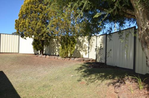 a fence with a tree in front of it at Sunray Motor Inn in Toowoomba