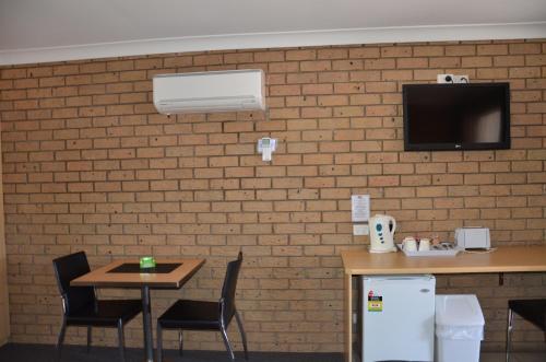 a room with two tables and a tv on a brick wall at Sunray Motor Inn in Toowoomba
