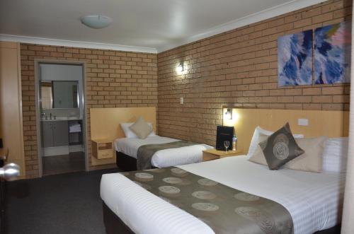 a hotel room with two beds and a brick wall at Sunray Motor Inn in Toowoomba