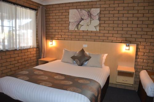 a hotel room with a bed and a brick wall at Sunray Motor Inn in Toowoomba