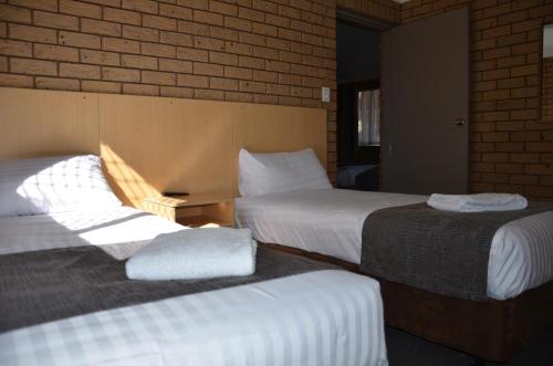 a hotel room with two beds and a brick wall at Sunray Motor Inn in Toowoomba