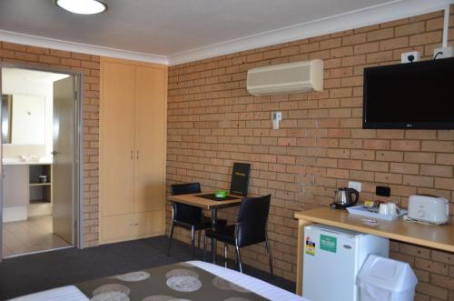 a hotel room with a small table and a tv on a brick wall at Sunray Motor Inn in Toowoomba