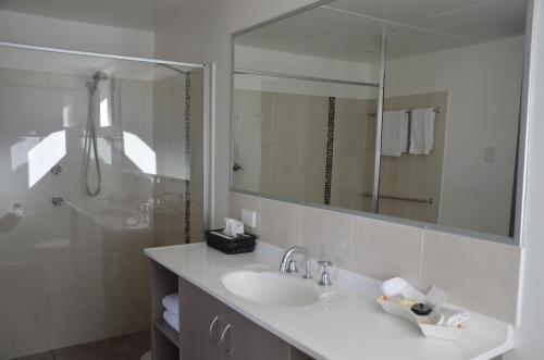 
a bathroom with a sink, mirror, and bathtub at Sunray Motor Inn in Toowoomba
