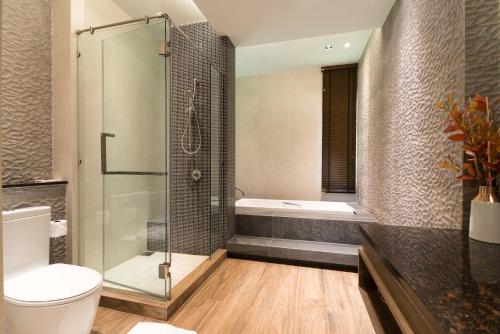 a bathroom with a shower and a toilet and a tub at Green Ville Laguna Hotel in Sung Noen
